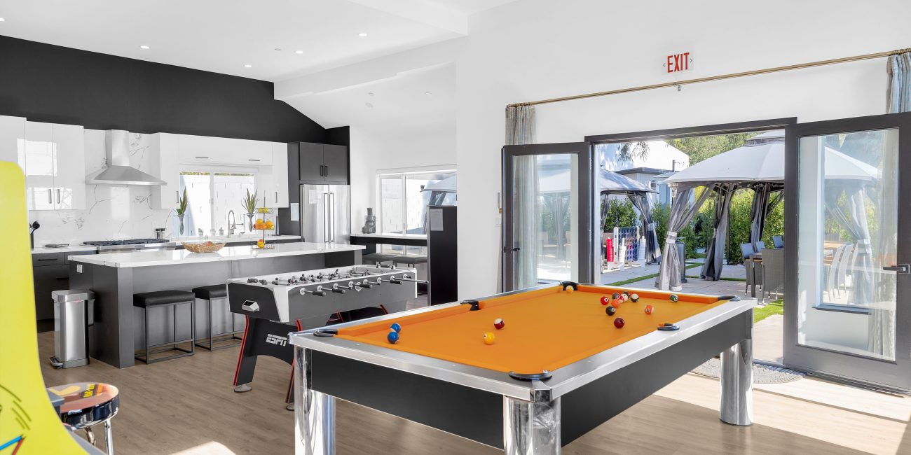 The game room featuring a pool table and foosball table facing the kitchen at Uplift Recovery Center