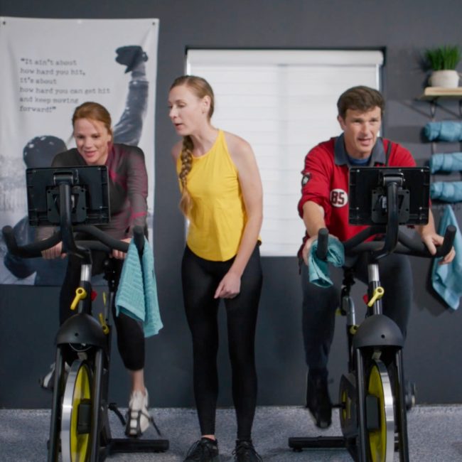 two men on exercise bikes under the care of a fitness trainer at Uplift Recovery Center