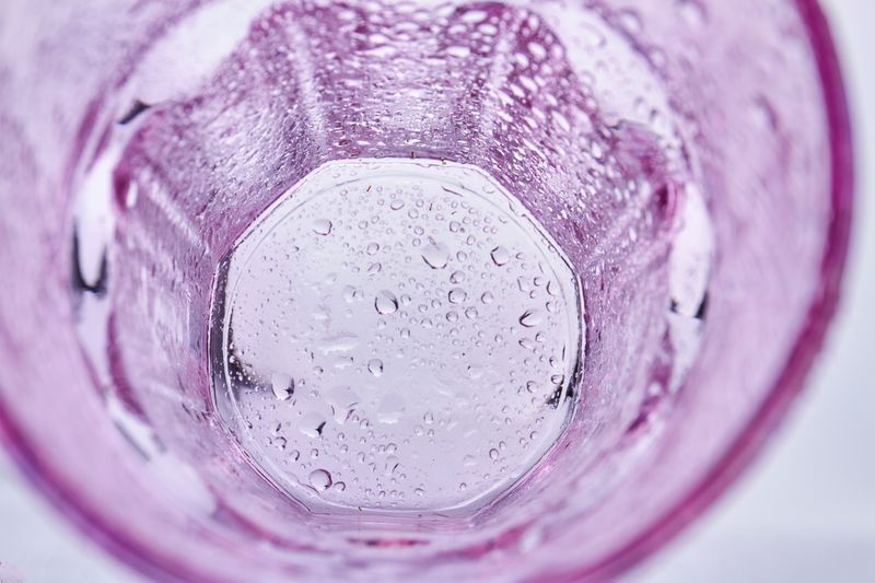 the bottom of an empty and pink alcohol glass