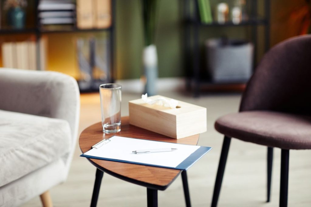 a table at a therapist office with a notepad, tissues and water an a coffee table