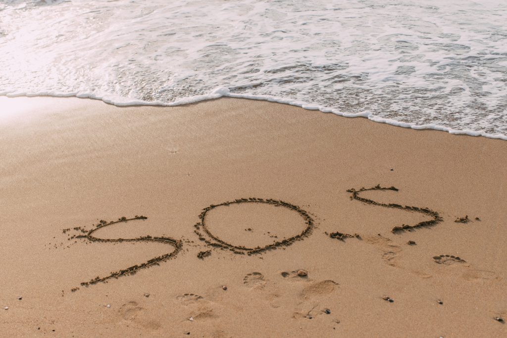 the words "SOS" written into the sand on the beach, highlighting the importance to address substance abuse in the military
