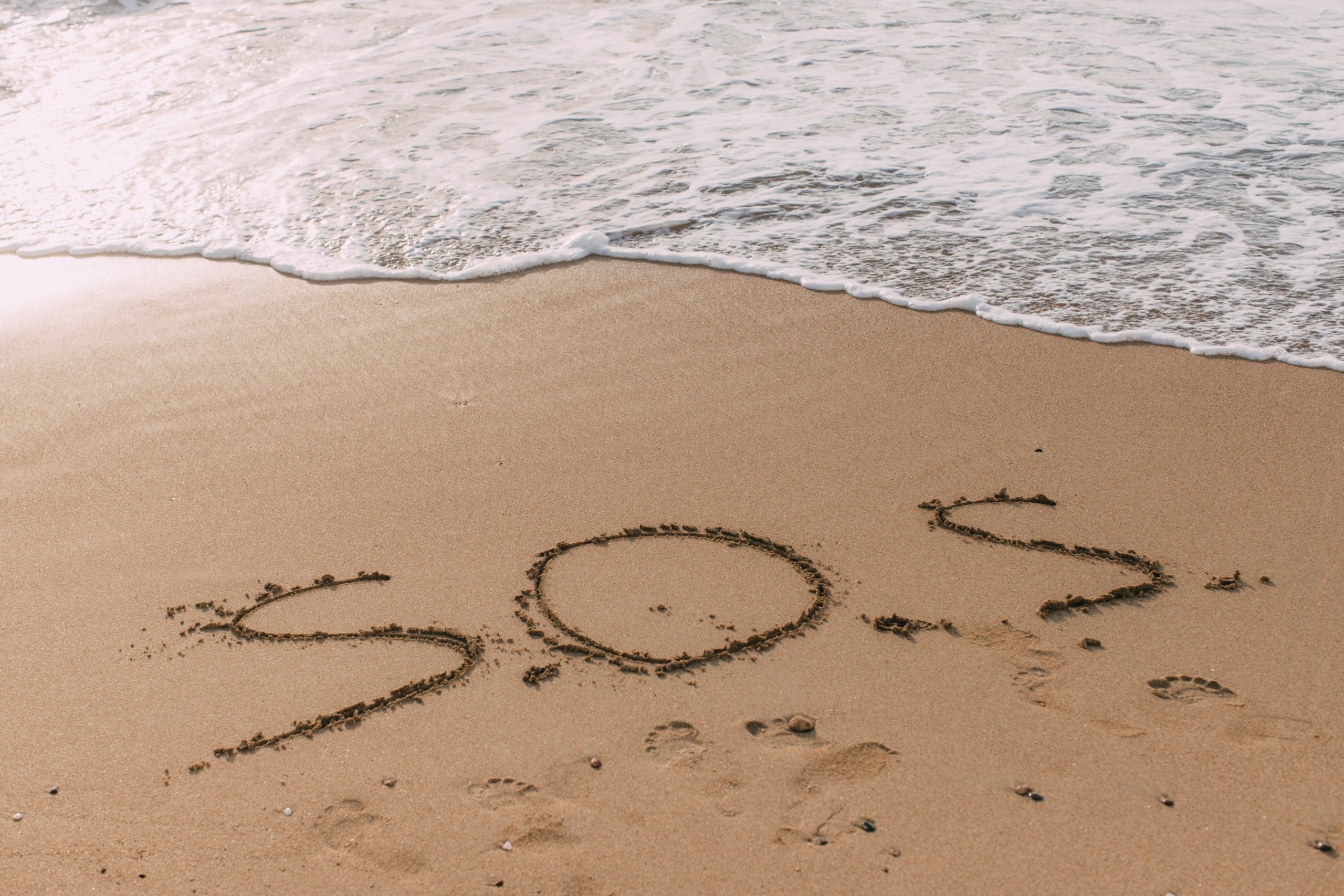 the words "SOS" written into the sand on the beach, highlighting the importance to address substance abuse in the military
