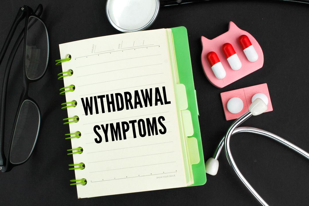 a notebook labeled "withdrawal symptoms" along with glasses, pills, and a stethoscope