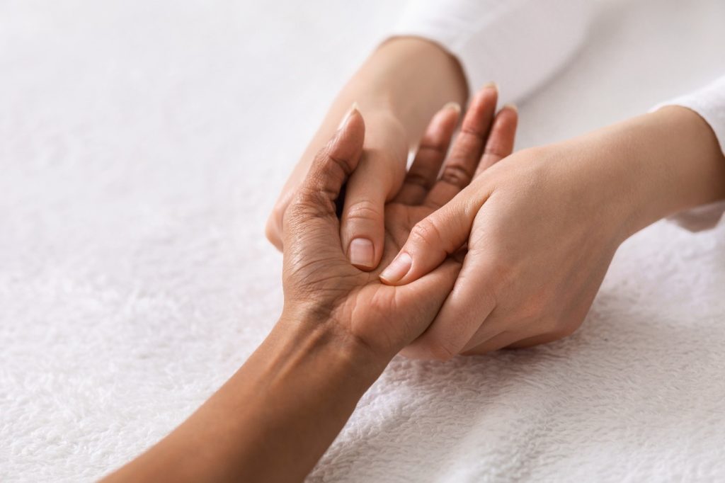 An acupuncturist feeling the hand of her patient who's getting acupuncture for addiction recovery