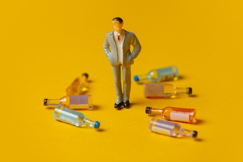 a man surrounded by empty bottles, signifying alcohol abuse