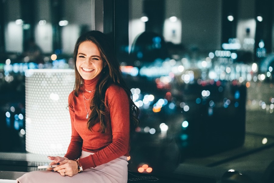 woman smiling against a glass window at night