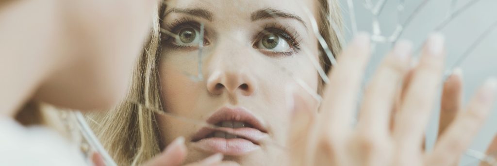 woman looking into a cracked mirror