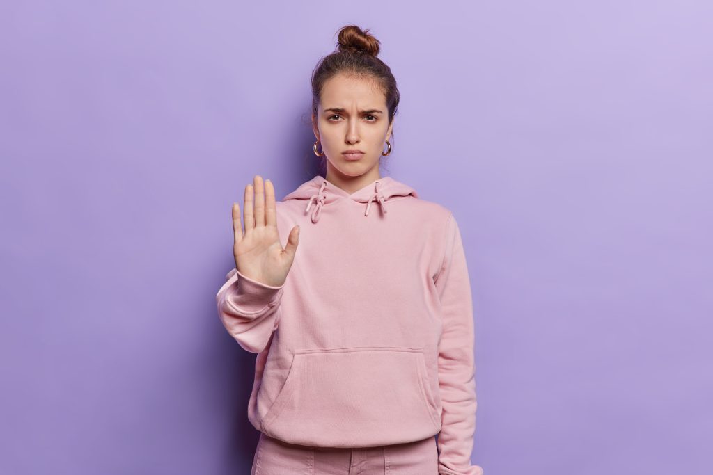 a woman holding up a hand to halt from addiction triggers