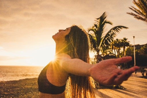 a woman at the beach at sunrise using somatic breathwork to aid in addiction recovery