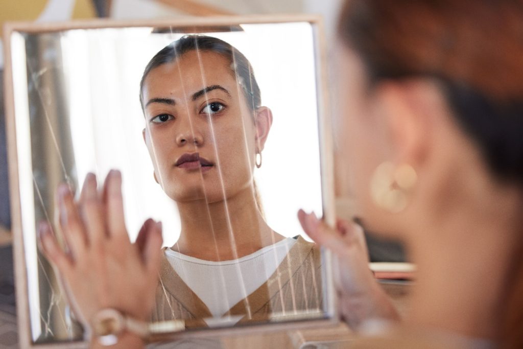 a woman looking into a cracked mirror, emphasizing the need for dual diagnosis treatment centers