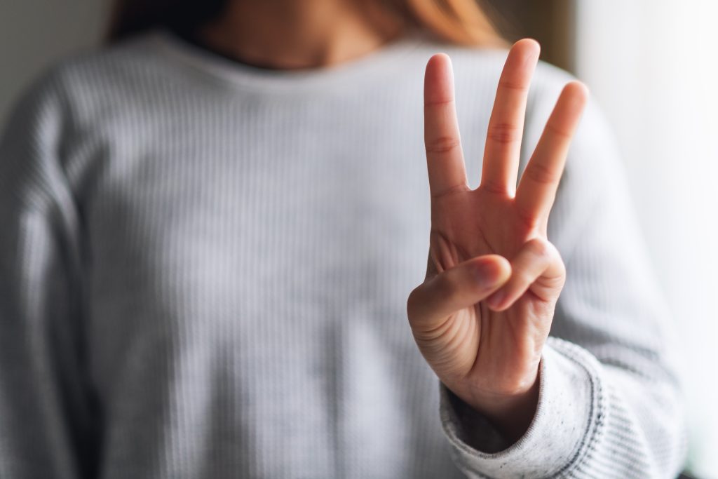 a woman holding up 3 fingers to show 3 examples of active and passive recovery techniques