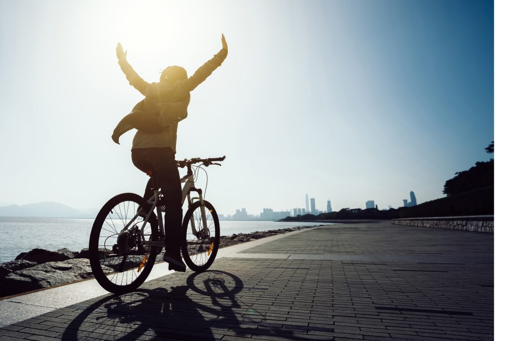a woman spreading her arms in joy while riding a bike as she experienced primary and secondary emotions in sobriety