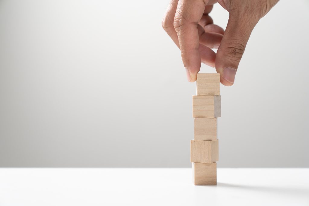 a hand stacking five blocks representing the stages of addiction