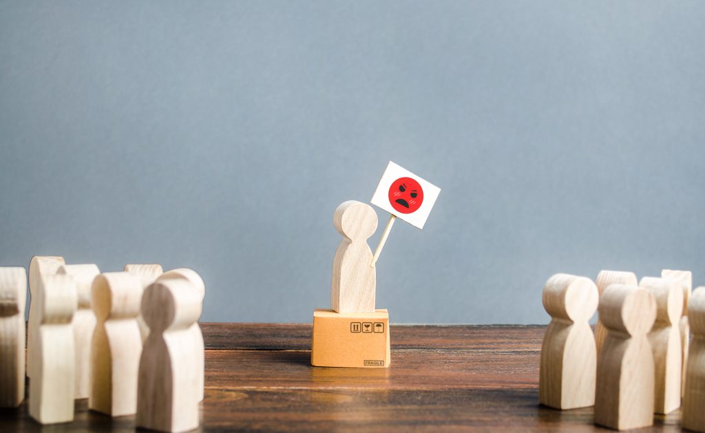 a wooden pawn holding up an angry face sign in front of others, showing the power in Aggression Replacement Therapy