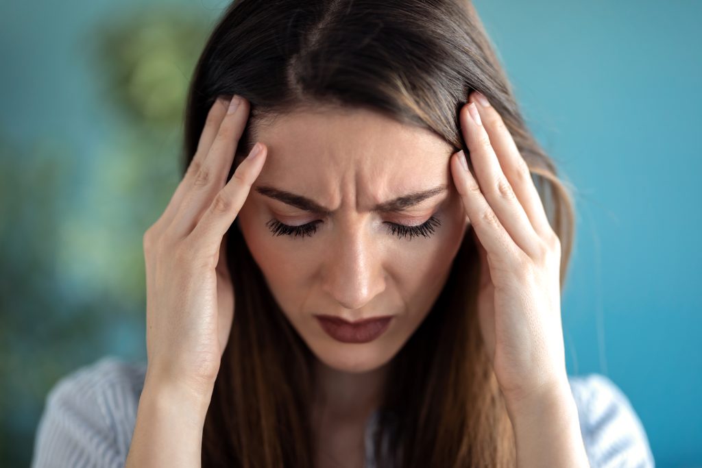a young woman with her hands on her head experiencing physical relapse from addiction