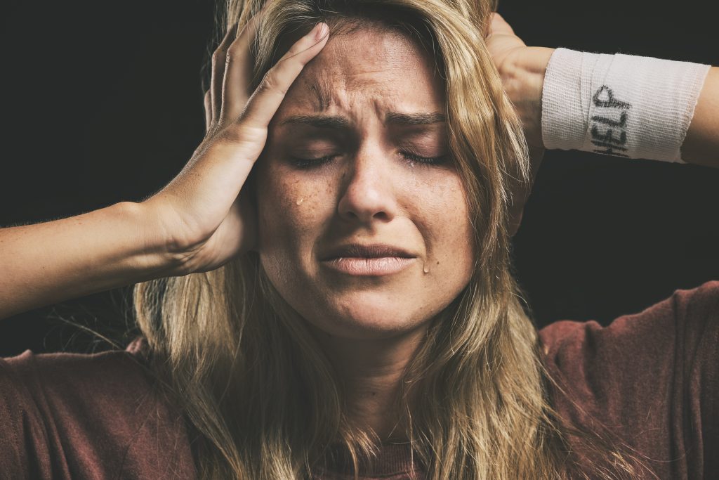 a depressed woman with her hands on her head, highlighting the dangers of women and substance abuse