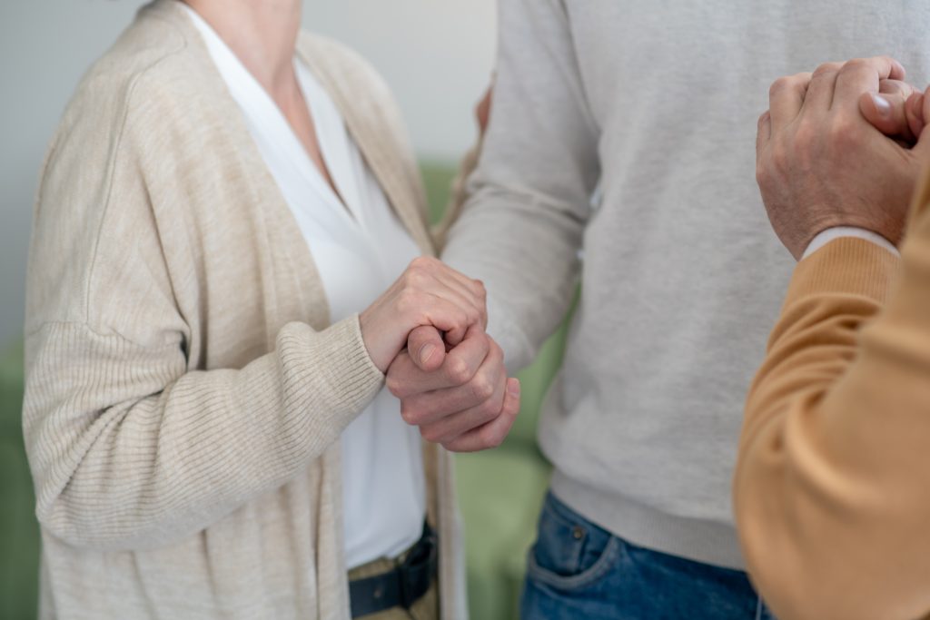 people holding hands and hugging as they have figured out how to help a loved one with addiction