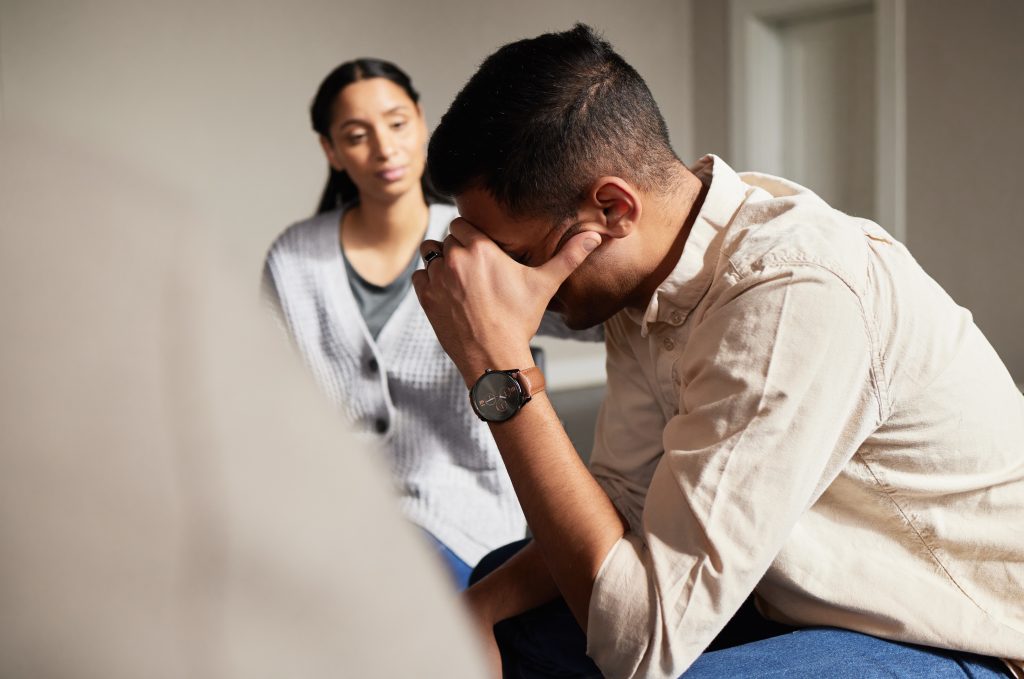a man sunk into his hands during group therapy and is experiencing emotional relapse