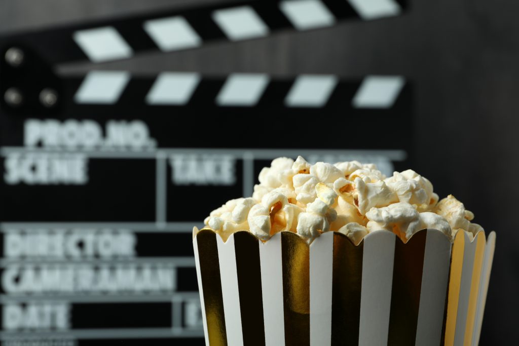 A bucket of popcorn and a slate in the background representing the best addiction movies