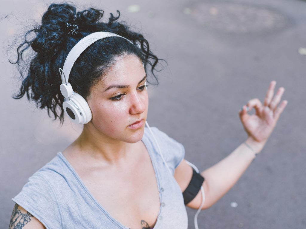 A woman meditating while listening to addiction songs on her headphones