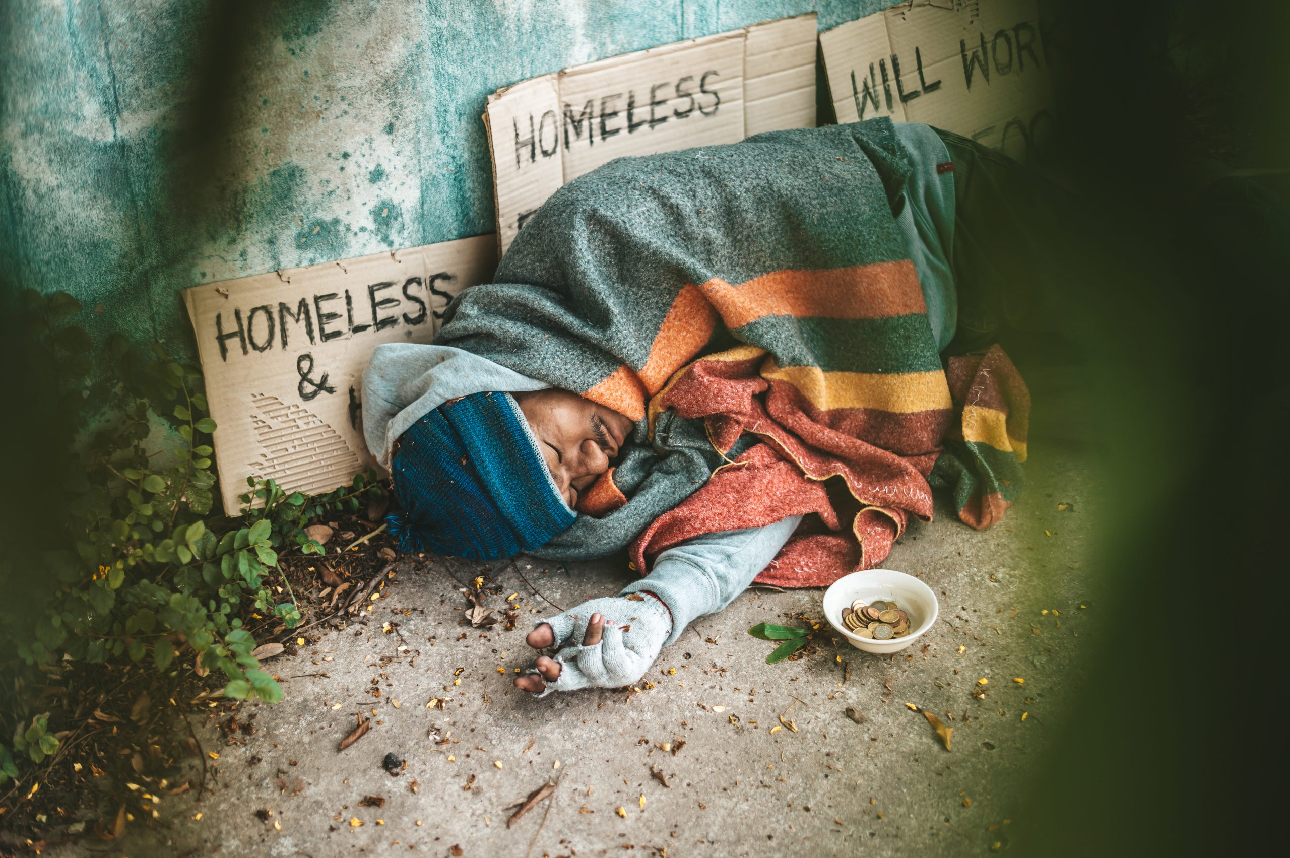 a beggar sleeping on the sidewalk, emphasizing the connection between addiction and homelessness