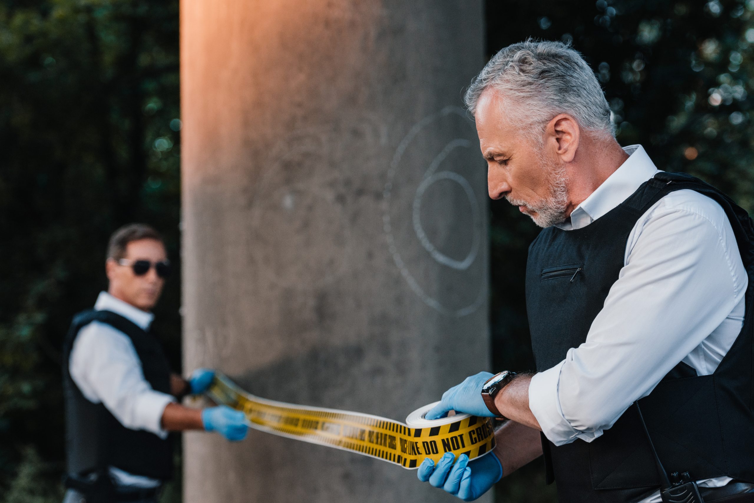 male police officers in latex gloves setting the police line at a crime scene, highlighting the correlation between substance abuse and crime