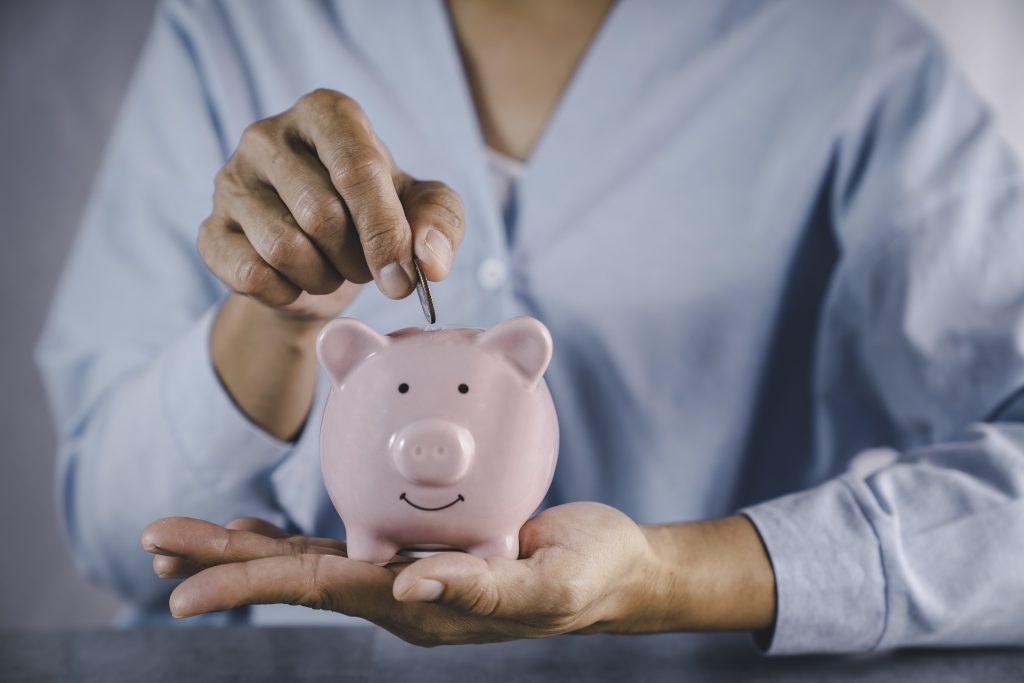 a woman placing a coin in a piggy bank as part of money management for recovering addicts