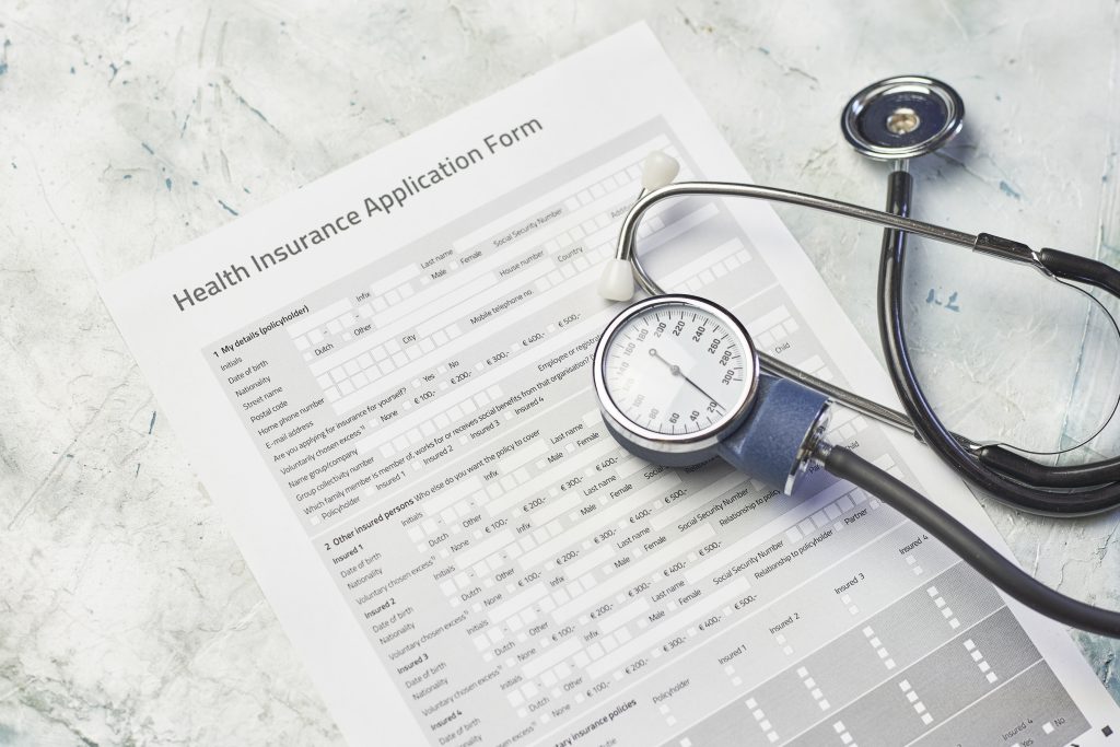 health insurance application form and a stethoscope asking the question "does Medicaid cover rehab?"