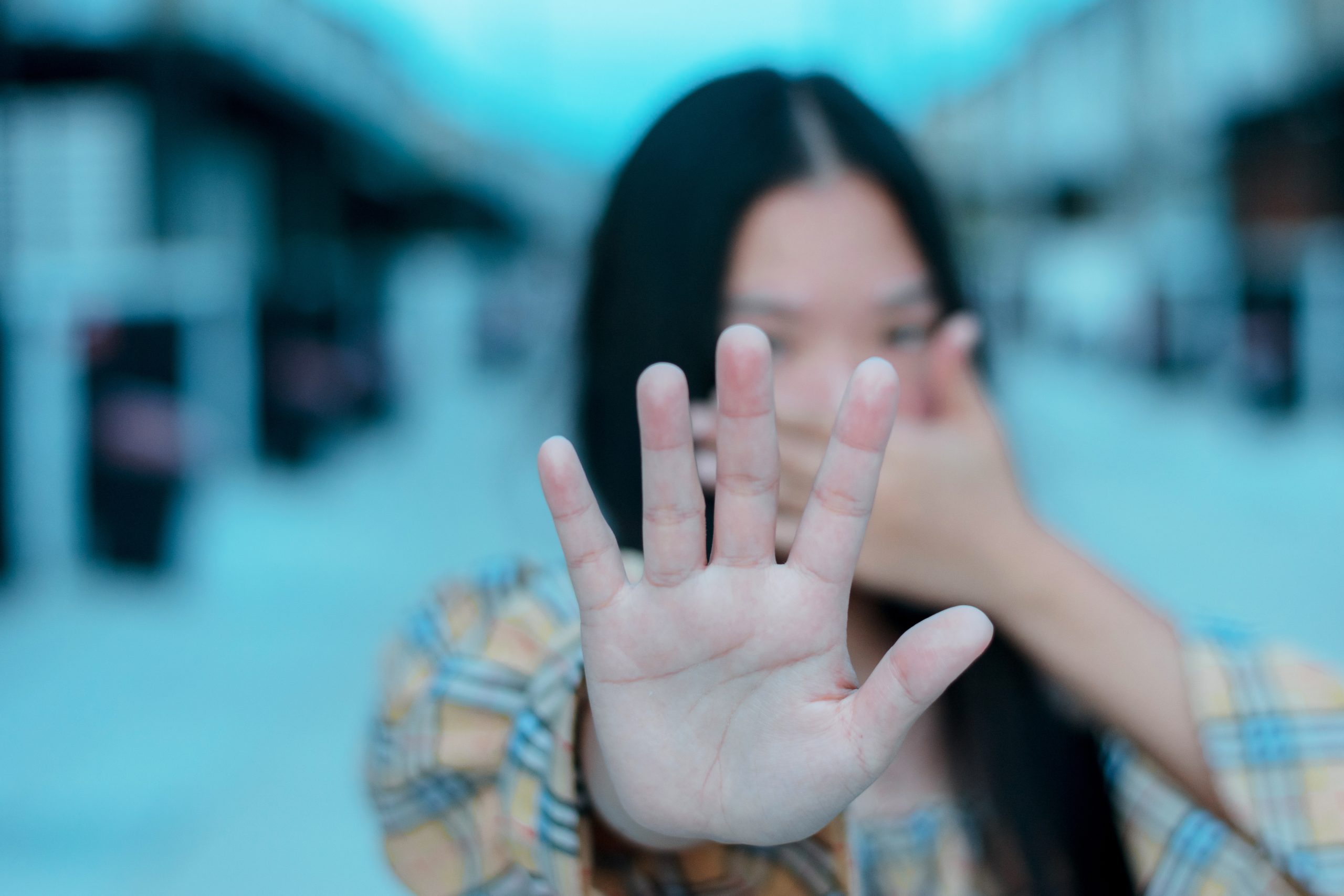 a young woman holding up a hand as a sign to beware of rainbow fentanyl