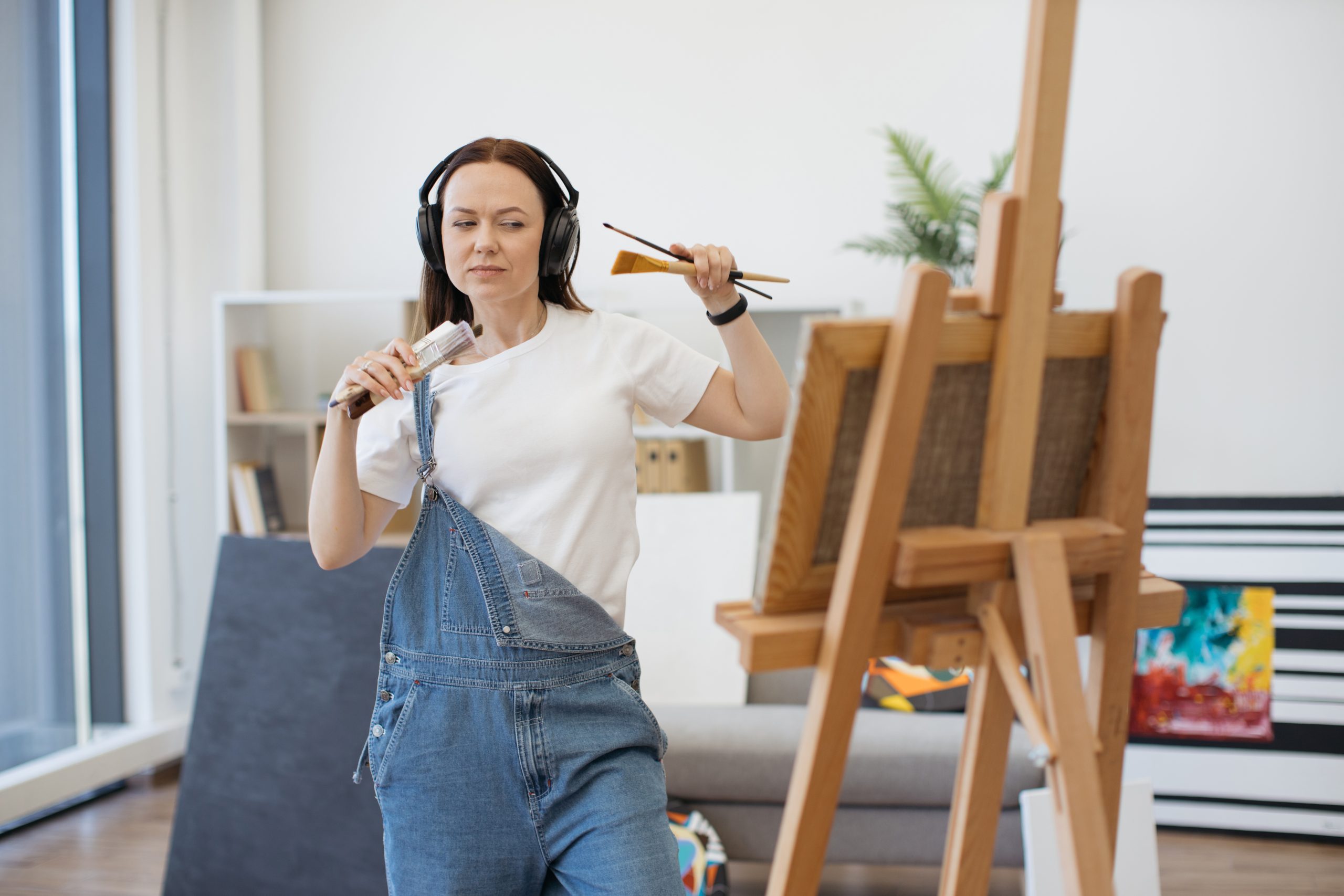 a woman painting as she listens to music during Anti-Boredom Month