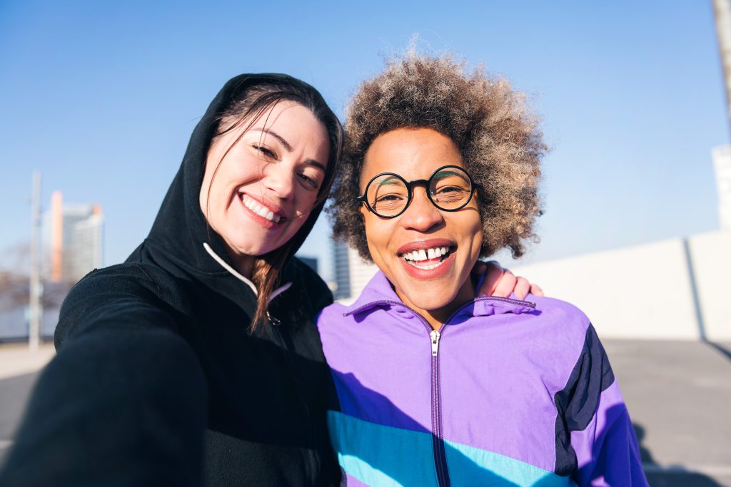 two women smiling beside each other to show the relationship between a sponsor and a sponsee in aa